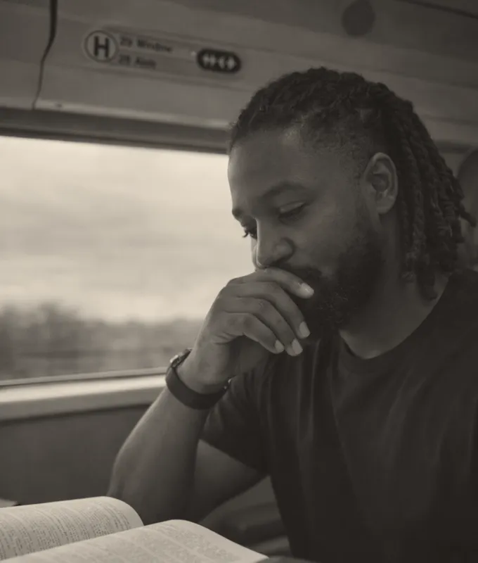 Abbey Ibrahim reading on a train, deep in work. Click to bring forward